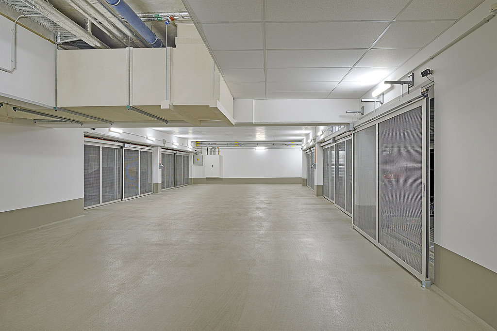 Zona de maniobras de un aparcamiento subterráneo con puertas de malla metálica