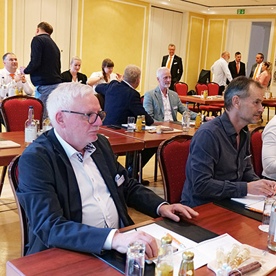 Viele Personen sitzen in einem Konferenzraum, ein paar weitere Personen ...